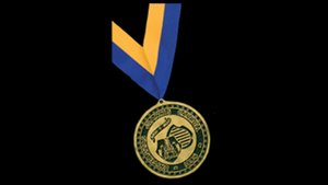 A circular gold medal, an alumni award for distinguished service, hangs from a blue and gold striped ribbon.