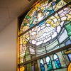A stained-glass window shows an angel with flowers and building architecture.