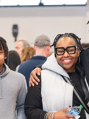 A family of four, including two prospective students, smiles brightly at a JCU campus event. One student wears a name tag.