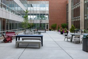 View of an outdoor courtyard at John Carroll University with tables, benches, chairs, planters, and surrounding campus.