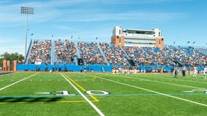 View of Don Shula Stadium filled with spectators watching a football game on a sunny day.