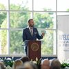 A speaker addresses JCU alumni and friends from a podium, gesturing with his hand.