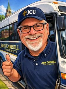 A smiling man with glasses and a white beard wearing a John Carroll University cap and shirt gives a thumbs-up by a bus.