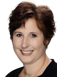 A woman with short brown hair smiles at the camera against a plain white background.