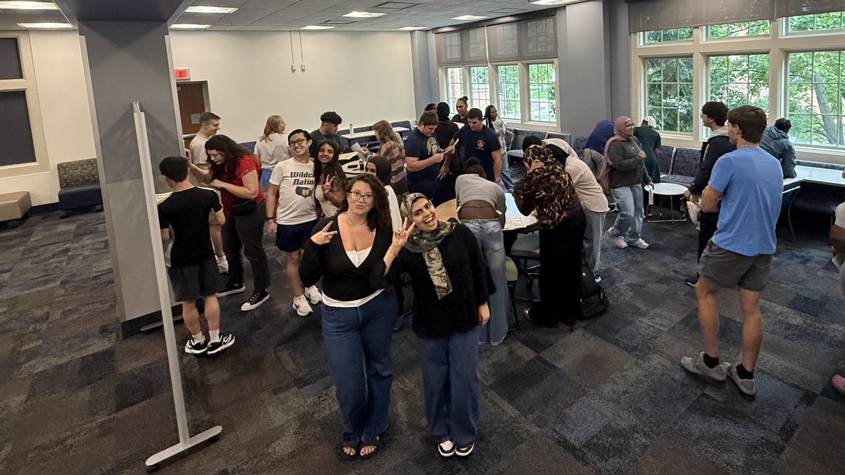 Students mingling during a group activity, two smiling at the camera.