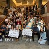 A large group of people sitting and standing on stairs inside a building hold signs that say Congrats JCU Nursing and Fully.