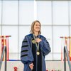 A university leader, wearing academic regalia and a ceremonial chain, smiles with her hand over her heart during