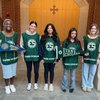 Five young women wearing green Evans Scholar vests stand in a row inside a brick and stone building holding college pennants.