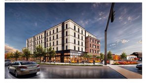 A modern five-story building with large windows stands at a street corner with cars and people walking on the sidewalks.