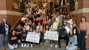 Joyful nursing students celebrate their program’s full accreditation on a university staircase