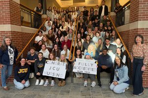 Joyful nursing students celebrate their program’s full accreditation on a university staircase