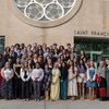 A large group of people posing and smiling in front of a building labeled Saint Francis Chapel.