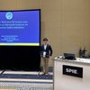 A man in a suit stands smiling next to a presentation screen titled HoloPose about 3D human pose estimation.
