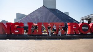 Seven students pose with the red lettering outside the Rock and Roll Hall of Fame; it spells out, "Long Live Rock.