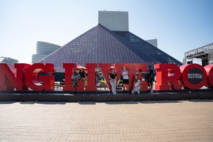 Seven students pose with the red lettering outside the Rock and Roll Hall of Fame; it spells out, "Long Live Rock.