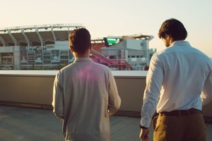 Two students walk away from the viewer, outside near a stadium, bathed in the warm glow of sunset.