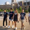 Five students walk off campus, smiling and talking near the Cleveland baseball stadium.