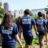 A group of people wearing matching blue shirts that say Living the Mission walk along a dirt path in a garden.