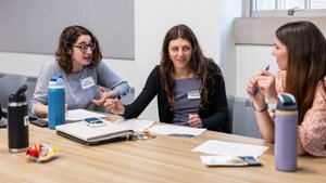 Three Women Sit Table Papers Water Bottles Engaged