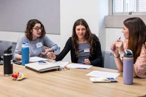 Three Women Sit Table Papers Water Bottles Engaged