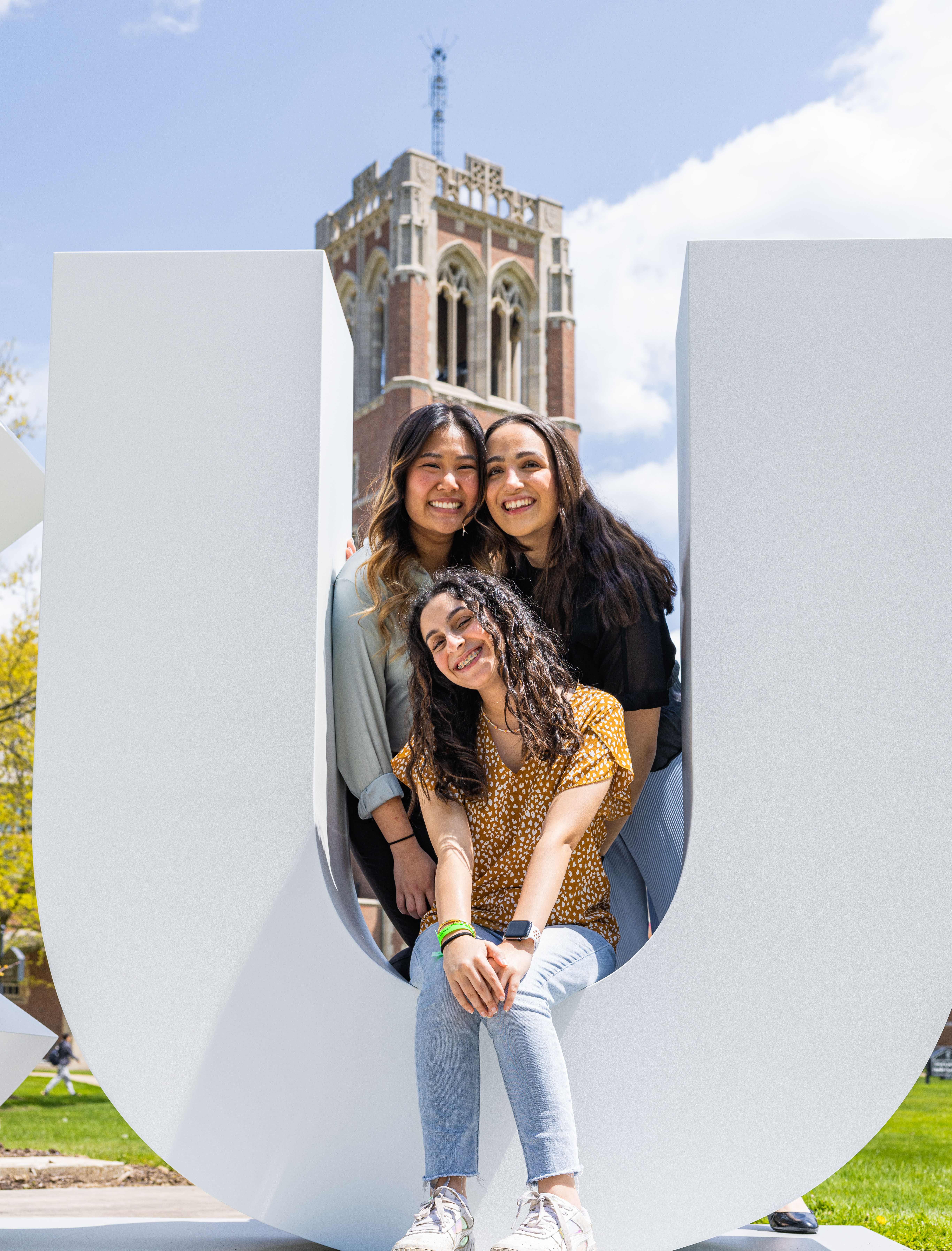 three female students smiling in front of the jcu clock tower
