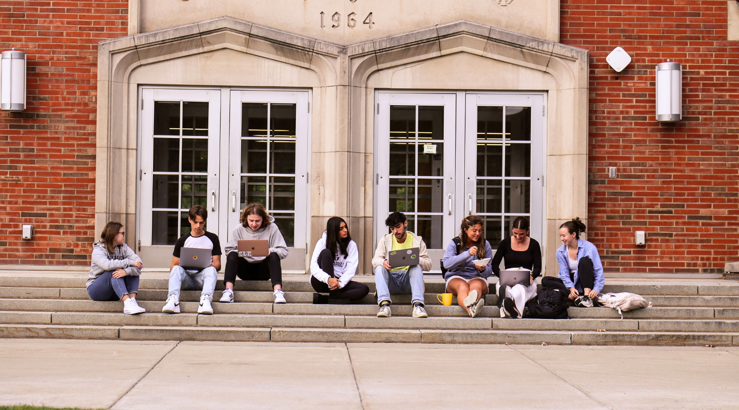 students sitting on the steps of a residence hall