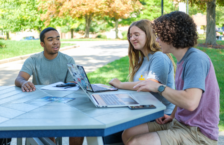 three JCU students meeting at a table on the quad during spring