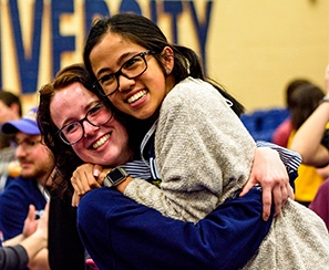 Two current student volunteers hugging during Celebration event for incoming students