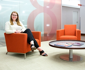 Graduate student photographed in orange lobby chair at her place of employment 
