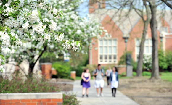 Group of students walking in front of the Administration Building with Rodman Hall in the background in the spring