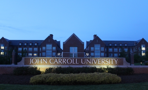 Picture of the front of campus with the John Carroll University sign and Dolan Science Center in the background at dusk