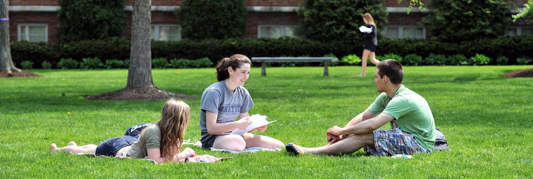 Three students studying on quad in spring