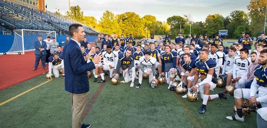 Tom Telesco stands on Wasmer Field and addresses the football team. 